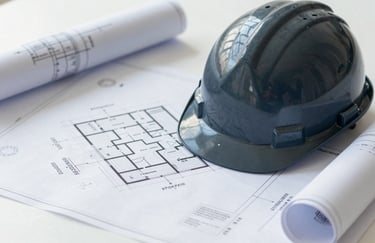 A flat-lay photograph of professional blueprints and a modern hard hat on a clean workspace. The aesthetic is focused on engineering expertise, using colors #2D3A3A and #F0F5F5.