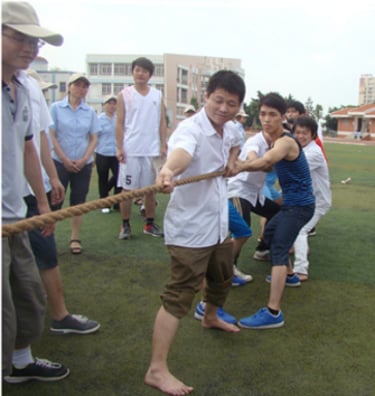 Staffs of Cooldbath participating in a competitive tug of war match on a grassy outdoor sports field