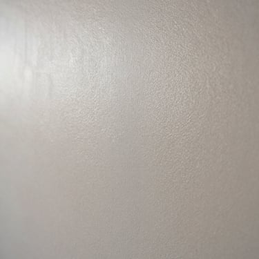 Close-up of a high-quality stucco finish on a wall, showing the smooth texture and subtle light reflection, professional craftsmanship.