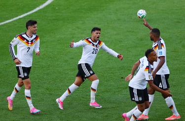 German national soccer team players celebrating on a green field during a professional football match.