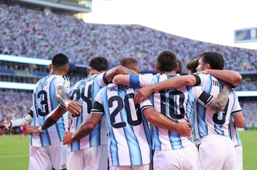Argentina national football team players in blue and white jerseys huddle during a match in a packed stadium.