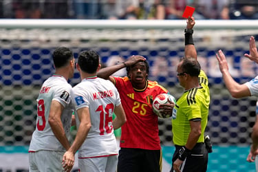 A soccer referee shows a red card to a shocked Belgium player during an international football match.