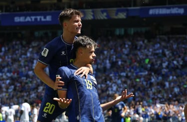 Professional soccer players in blue jerseys celebrating a goal in a packed stadium during a match.