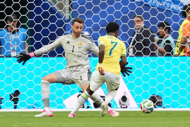Brazil's Vinicius Junior dribbles past the Scotland goalkeeper during a football match.