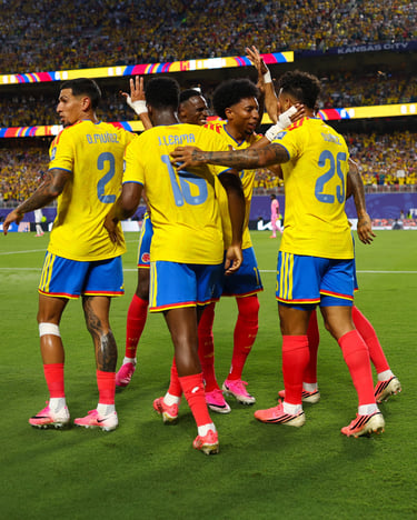 Colombia national football team players in yellow jerseys celebrating a goal on a stadium pitch.