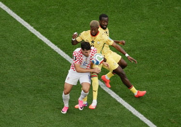Croatia and Ghana soccer players competing for the ball during a professional football match on a green field.