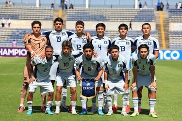 El Salvador national youth soccer team players in white uniforms posing for a group photo on a sunny field.