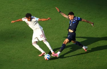 Two professional soccer players competing for the ball during a high-stakes match on a green field.
