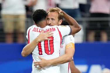 England football players Harry Kane and Jude Bellingham embrace during a match on the field.