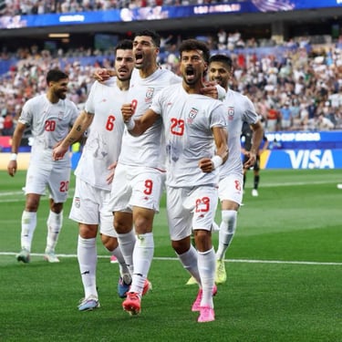 Iran national football team players in white jerseys celebrate a goal during a soccer match.