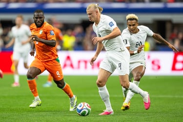 Erling Haaland dribbles a soccer ball past defenders during a high-action international match.