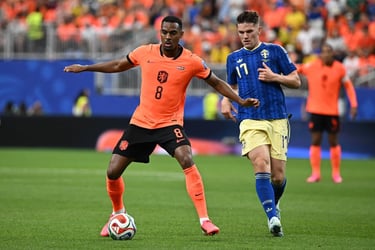 A Dutch soccer player in an orange jersey dribbles the ball past a Swedish opponent in blue during a match.