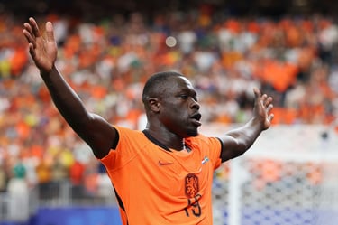 Dutch football player Brian Brobbey celebrates on the pitch in an orange Netherlands national team jersey.