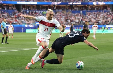 Turkey national football team player dribbles past a falling opponent during a competitive soccer match.