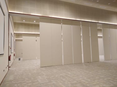 Movable acoustic wall panels installed in a modern conference hall for flexible room division.
