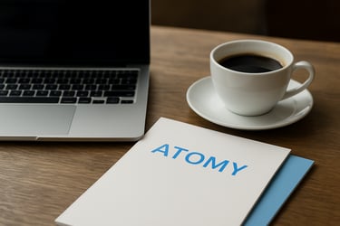 A business workspace featuring a laptop, a cup of Colombian coffee, and Atomy catalogs, representing the distributor lifestyle.