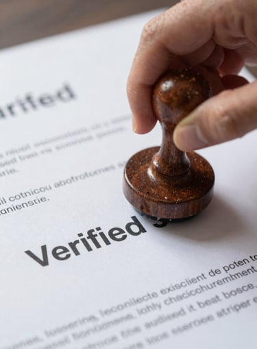 A minimalist, high-contrast shot of a 'Verified' stamp hitting a document, focusing on the trust and precision of the consultancy firm.