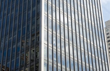 Modern architectural detail of a glass corporate building in a Brazilian business district, midday sun, clean and professional look with silver and navy blue tones.