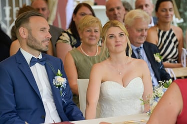 Hochzeitsfotograf Möhnesee: Brautpaar blickt gerührt zur Traurednerin; emotionale Nahaufnahme während der Zeremonie.