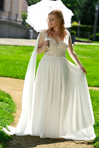 Hochzeitsfotograf Möhnesee: Porträt einer Braut mit rotem Haar; Vintage-Spitzenkleid und weißer Spitzensonnenschirm im Park.