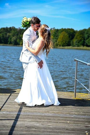 Hochzeitsfotograf am Möhnesee: Brautpaar küsst sich auf einem Holzsteg direkt am Wasser; romantisches Shooting am Seeufer.