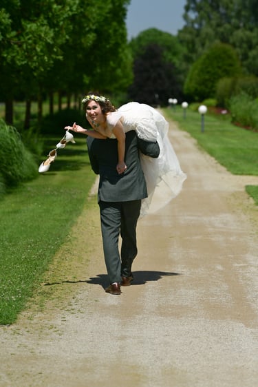 Hochzeitsfotos Möhnesee: Bräutigam trägt lachende Braut über die Schulter; verspieltes Shooting im sonnigen Park.