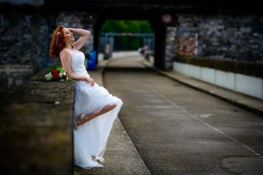 Braut in elegantem Spitzenkleid lehnt entspannt an der Möhnetalsperre – emotionale Hochzeitsfotografie von Lunora Weddings am