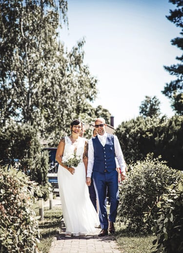 Brautpaar geht Hand in Hand nach der Trauung einen Gartenweg entlang.