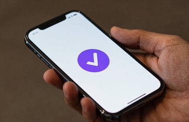 Macro photography of a sleek smartphone held by a Latin American / Spanish-speaking user, showing a secure payment confirmation with a purple checkmark icon.