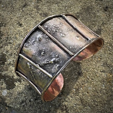 A wide copper cuff textured with copper and silver dust