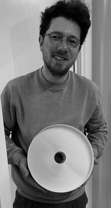 Smiling man with glasses holding a large roll of white industrial paper or tape.