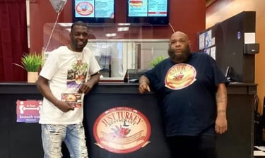 Two men standing at the counter of The Original Just Turkey Restaurant in front of digital menus.