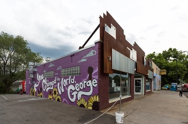 A purple mural on a brick building reads You Changed the World George in honor of George Floyd.