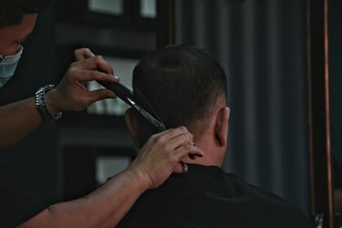 Professional barber using scissors and a comb for a precision men's haircut in a barbershop.