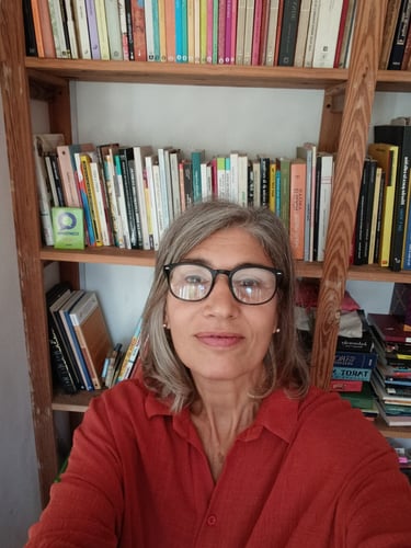 Fotografía de Silvina Maroni, editoria de Obsidiana, delante de una biblioteca con libros