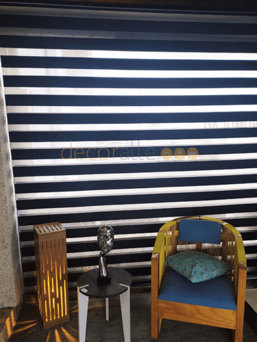persina modelo rolo sher double vision na cor preto de tecido blackout em um ambiente decorado acompanhado de uma luminaria m