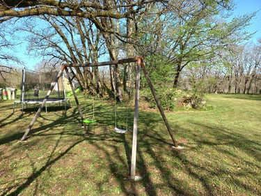 Aire de jeux ombragée dans un parc de 4500 m² avec trampoline, toboggans et cabane pour enfants.
