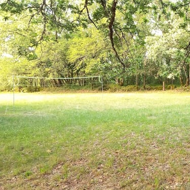 Terrain de badminton ou volley extérieur avec filet installé sur une grande pelouse ombragée.dans l'après midi