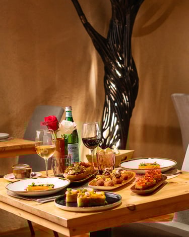 Mesa servida con el menú degustación de Es Mestral: croquetas, milhojas y vino en comedor interior,Es Mestral en Ses Salines.