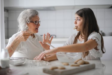 Grandmother and granddaughter baking homemade cookies together in a bright kitchen.