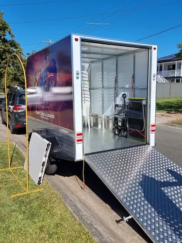 Gold arch hoop backdrop and folding table outside trailer at collection in Redland Bay.
