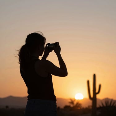 silhouette of person holding camera during golden hour
