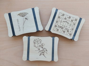 Three small wooden flower presses with bands with floral images on the fronts