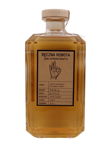 Szklana butelka wódki o smaku orzecha włoskiego z drewnianym korkiem i ręcznie napisaną etykietą.