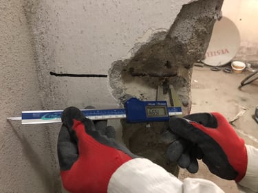 Yapısal inceleme için hasarlı bir beton kolon içindeki çelik donatıyı ölçen dijital kumpas.