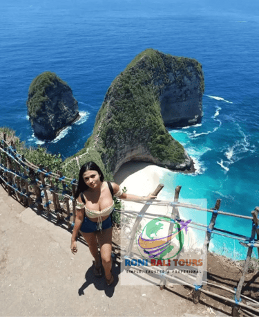 Woman posing at Kelingking Beach viewpoint overlooking the iconic T-Rex bay in Nusa Penida, Bali.