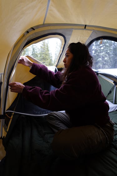 Young girl zipping up window inside a Thule Approach M Rooftop Tent 