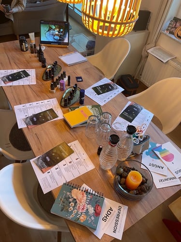 A wooden table set up for a dōTERRA essential oils workshop with brochures, glass bottles, and notebooks.
