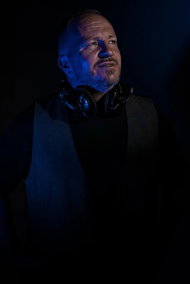 Künstlerporträt eines DJs mit Kopfhörern und kreativem Lichteffekt in Blau, Studioaufnahme Berlin.