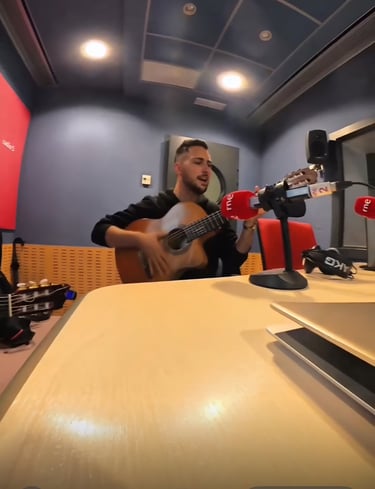 Musician playing s guitar and singing into a professional microphone at an RNE radio station studio.